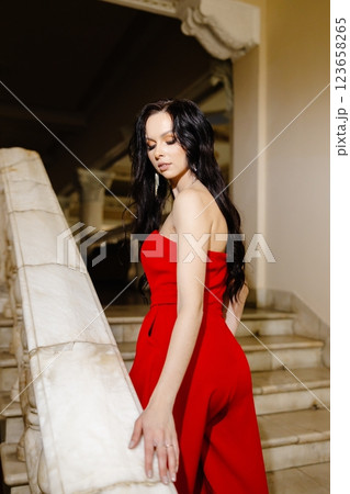 Elegant woman in red suit is standing on the big stairs. 123658265