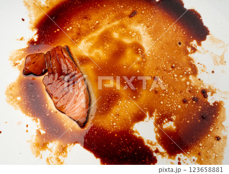 Spilled Soy Sause Leftovers with a Piece of Fish Isolated, Teriyaki Drops on White Plate, Oyster Sauce 123658881
