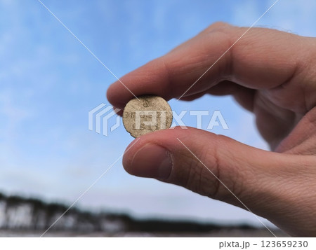 An old silver coin, a hand holding an ancient silver coin in a field. An ancient coin in your hands. An old silver coin An old silver coin, a hand holding an ancient silver coin in a field. An ancient coin in your hands. An old silver coin 123659230