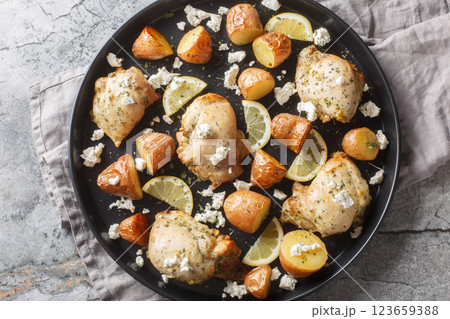 Skinless chicken thighs baked with feta, lemon, garlic and potatoes close-up in a frying pan. Horizontal top view Skinless chicken thighs baked with feta, lemon, garlic and potatoes close-up in a frying pan. Horizontal top view 123659388