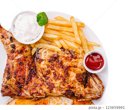 Chicken dish with fries and sauces served on a white plate Chicken dish with fries and sauces served on a white plate 123659991