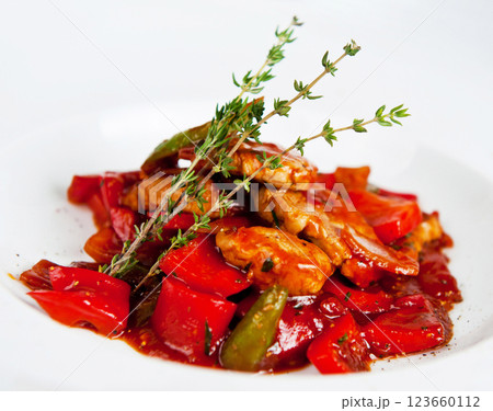 Chicken fillet with vegetables on a white plate being decorated with thyme sprigs 123660112