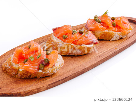 Delicious salmon tartines served on a wooden platter with capers Delicious salmon tartines served on a wooden platter with capers 123660124
