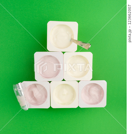 Yogurt cups set, pink and yellow fruit yoghurt in plastic pots, milk pudding container with spoon Yogurt cups set, pink and yellow fruit yoghurt in plastic pots, milk pudding container with spoon 123662007