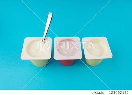 Yogurt cups set, pink and yellow fruit yoghurt in plastic pots, milk pudding container with spoon 123662125