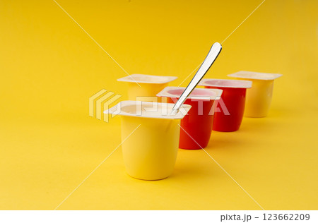 Yogurt cups set, pink and yellow fruit yoghurt in plastic pots, milk pudding container with spoon Yogurt cups set, pink and yellow fruit yoghurt in plastic pots, milk pudding container with spoon 123662209
