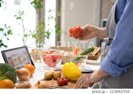 タブレットを見ながら料理をするミドル女性 タブレットを見ながら料理をするミドル女性 123662350