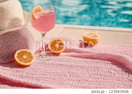 A glass filled with pink beverage decorated with a hat, pink towel, a mesh bag on the scarf. Concept of recovery, sun protection and moisturizing product with vacant space 123663686