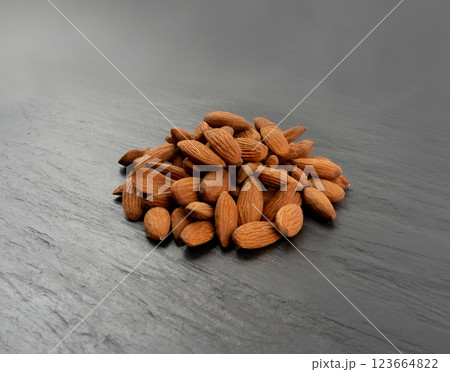 Almonds pile, nut group, whole almond seeds, brown scattered fruit kernels, dry raw nuts on black Almonds pile, nut group, whole almond seeds, brown scattered fruit kernels, dry raw nuts on black 123664822