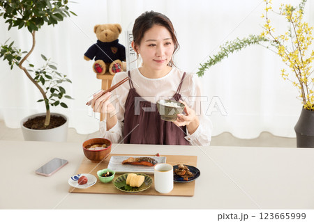 朝食にスマートフォンを見る女性 朝食にスマートフォンを見る女性 123665999