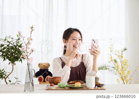 朝食にスマートフォンを見る女性 朝食にスマートフォンを見る女性 123666010