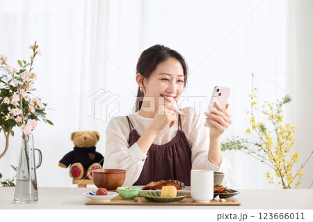 朝食にスマートフォンを見る女性 朝食にスマートフォンを見る女性 123666011