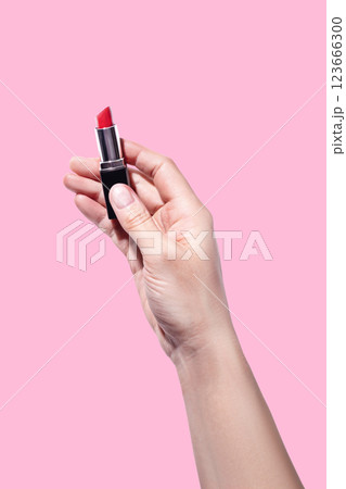 A woman's hand holds red lipstick isolated on pink background vertical photo A woman's hand holds red lipstick isolated on pink background vertical photo 123666300