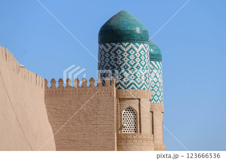 Towering turquoise minarets adorned with blue and white mosaic tiles against clear blue sky. Brickwork and traditional design highlight architectural beauty and cultural significance of the structure 123666536