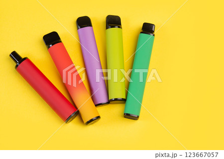 Layout of colorful disposable electronic cigarettes on a yellow background. The concept of modern smoking Layout of colorful disposable electronic cigarettes on a yellow background. The concept of modern smoking 123667057