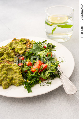 Enjoy a healthy breakfast with zucchini pancakes topped with green pea pesto, served with a mixed salad of fresh seasonal vegetables and herbs for a nutritious start 123668237