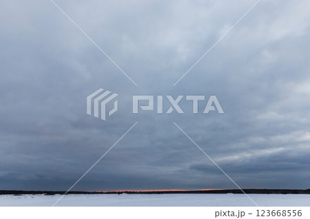 A serene winter scene featuring a vast snowy field under a cloudy sky A serene winter scene featuring a vast snowy field under a cloudy sky 123668556