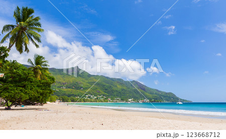 A tranquil tropical beach with lush green mountains in the background, 123668712