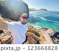 Man Taking Selfie on Rocky Cliff with Turquoise Sea View in Gazipasa Turkey on Sunny Day 123668828