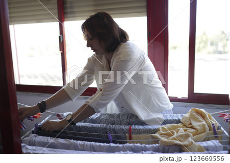 Woman hanging clothes on clothesline at home, managing household chores 123669556