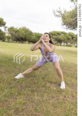 A Young Woman Is Doing a Stretching Routine in a Beautiful Park Bathed in Sunlight on a Lovely Sunny Day 123669761