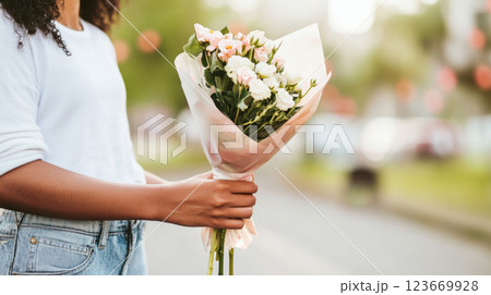 Bouquet of white and pink flowers held by African American woman outdoors 123669928