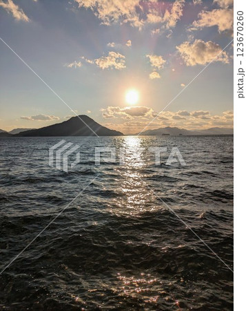 太陽が沈んでいく海と山のシルエット、美しいサンセット縦型 123670260