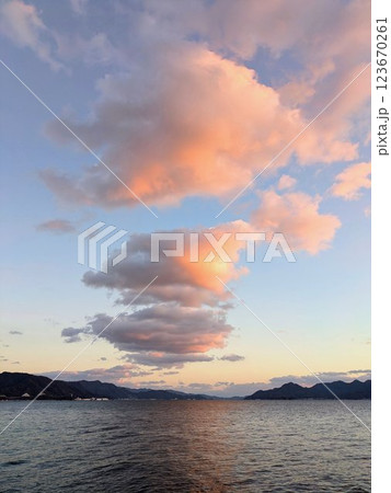 夕暮れの空に浮かぶ幻想的な雲と海の風景縦型 123670261