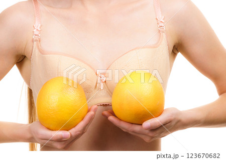 Woman small boobs holds big orange fruits 123670682