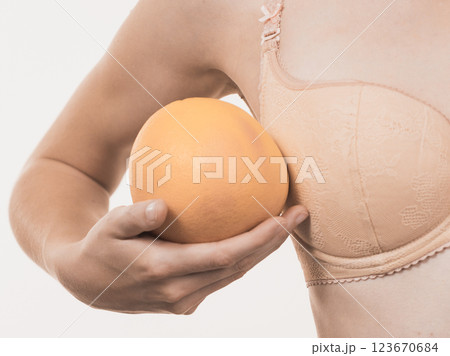 Woman small boobs holds big orange fruits Woman small boobs holds big orange fruits 123670684