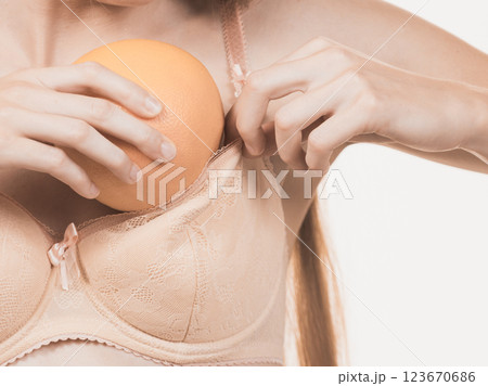 Woman small boobs puts big fruit in her bra Woman small boobs puts big fruit in her bra 123670686