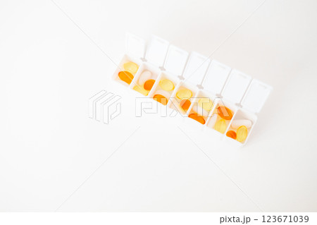 pillbox by days of the week with fish oil and various pills, on a white background. pillbox for keeping up with your vitamin regimen pillbox by days of the week with fish oil and various pills, on a white background. pillbox for keeping up with your vitamin regimen 123671039