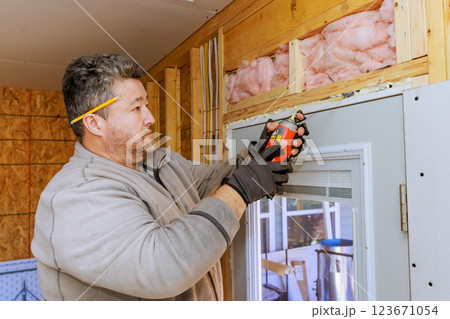 Contractor weatherproofing foam installs insulation spray while preparing window frame in home renovation 123671054