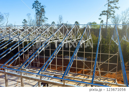 Workers construct steel framed structure surrounded by new metal warehouse it steel beams 123671056