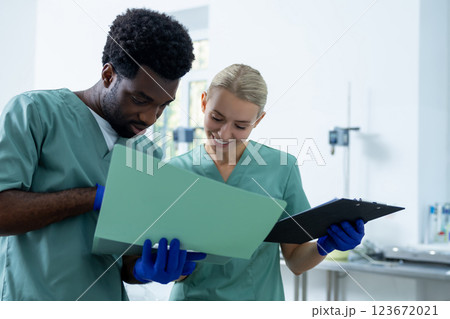 Male and female physicians having discussion with folder of documents in medical laboratory 123672021