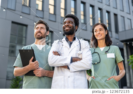 Group of young doctors in a clinic yard discussing patient case and looking interested Group of young doctors in a clinic yard discussing patient case and looking interested 123672135