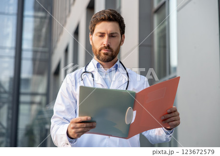 Determined male doctor in a lab coat with a prescription list in hands 123672579