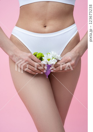 Female wearing absorbent underwear representing menstrual health care holding floral menstrual cup 123673238