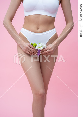 Unrecognizable woman holding menstrual eco-friendly reusable silicone cup with flowers 123673239