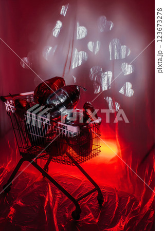 supermarket trolley full of foil balloons on red background. creative photo zone with hearts 123673278