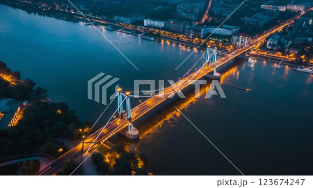 Elevated night shot capturing the radiance of a suspension bridge and the calm river 123674247