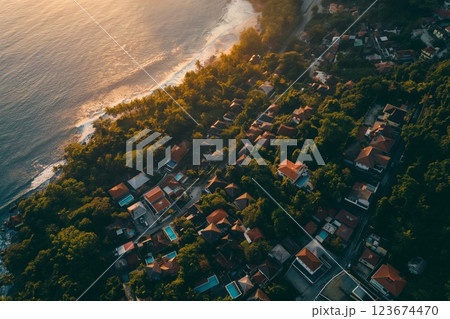 Aerial view of a serene tropical village by the beach bathed in golden sunset light 123674470
