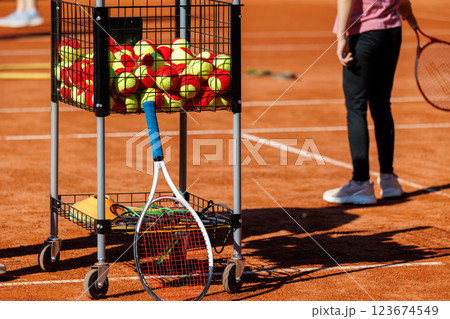 Basket cart filled colorful tennis balls Kids-training clay tennis court children playing training background. Summer sport camp. Sports youth school. Healthy child kid active lifestyle 123674549