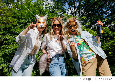 Three young adult beautiful woman girls friends enjoy have fun wearing animal mask laughing at picnic party city park green garden at sunny day. Female person friendship summer outdoors celebration Three young adult beautiful woman girls friends enjoy have fun wearing animal mask laughing at picnic party city park green garden at sunny day. Female person friendship summer outdoors celebration 123674552