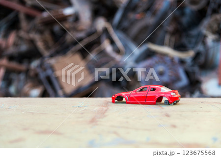 scrap metal heap at recycling junk yard and a damaged red toy car on the foreground. Selective focus. scrap metal heap at recycling junk yard and a damaged red toy car on the foreground. Selective focus. 123675568