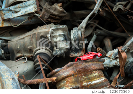 scrap metal heap at recycling junk yard and a damaged red toy car on the foreground. Selective focus. 123675569