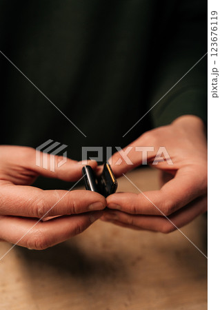 High-angle view of unrecognizable repairman preparation to replacement smartwatch battery, showing precision workmanship during delicate electronic maintenance process. Concept of repairing, upgrade. High-angle view of unrecognizable repairman preparation to replacement smartwatch battery, showing precision workmanship during delicate electronic maintenance process. Concept of repairing, upgrade. 123676119