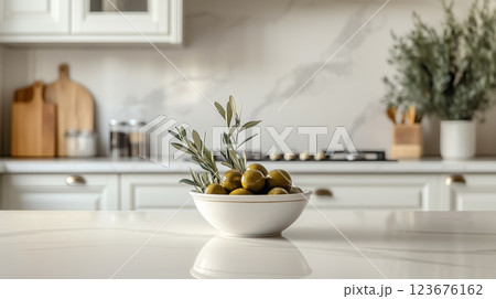 A traditional kitchen with a bowl of olives and an olive branch on the countertop.  123676162