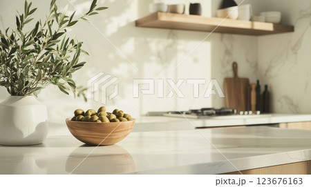 A traditional kitchen with a bowl of olives and an olive branch on the countertop.  123676163