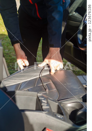 Person adjusting a black leather car seat, interior vehicle maintenance. High quality photo 123676186
